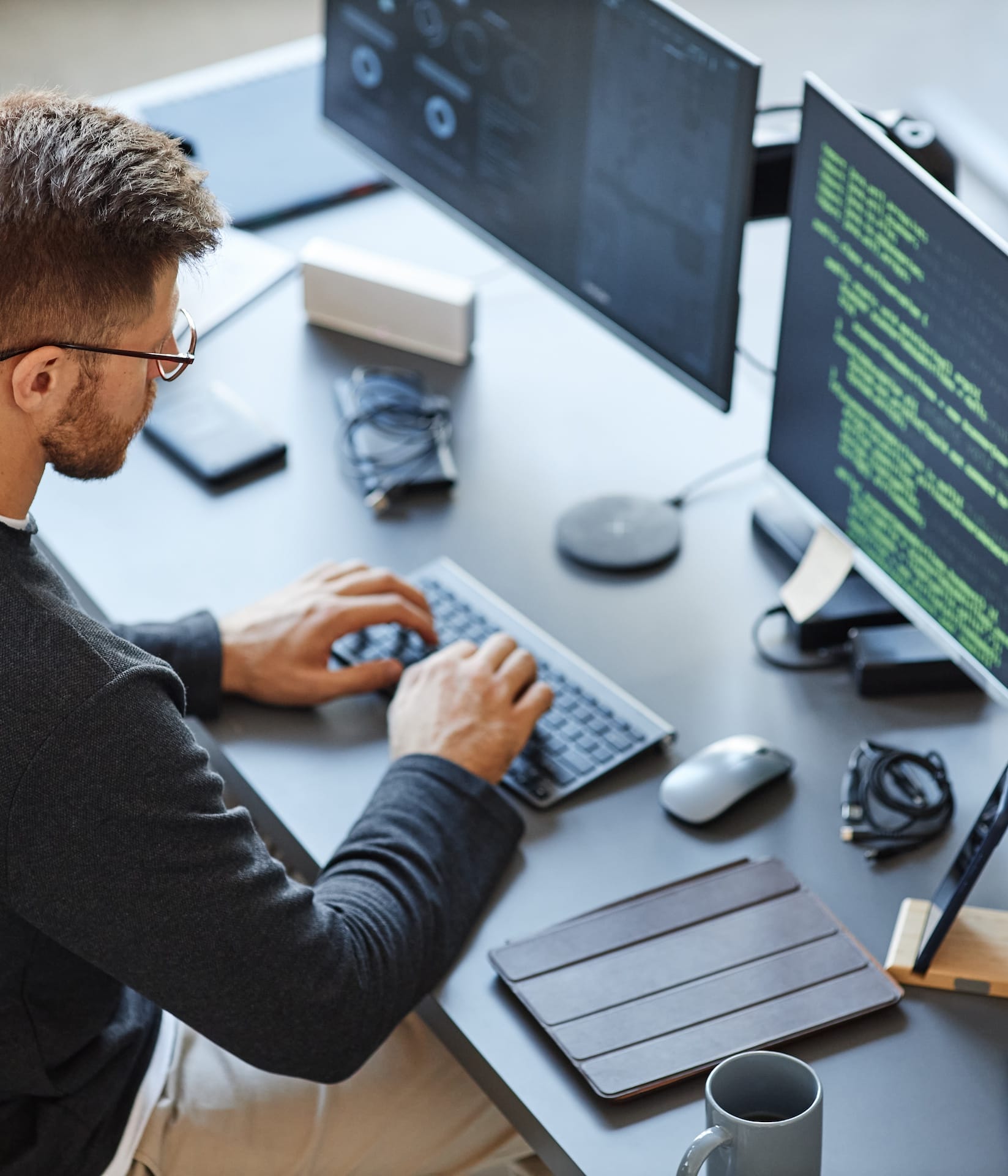 Mitarbeiter, der am Computerarbeitsplatz an seinem Schreibtisch sitzt und Programmcode eintippt Mitarbeiter, der am Computerarbeitsplatz an seinem Schreibtisch sitzt und Programmcode eintippt